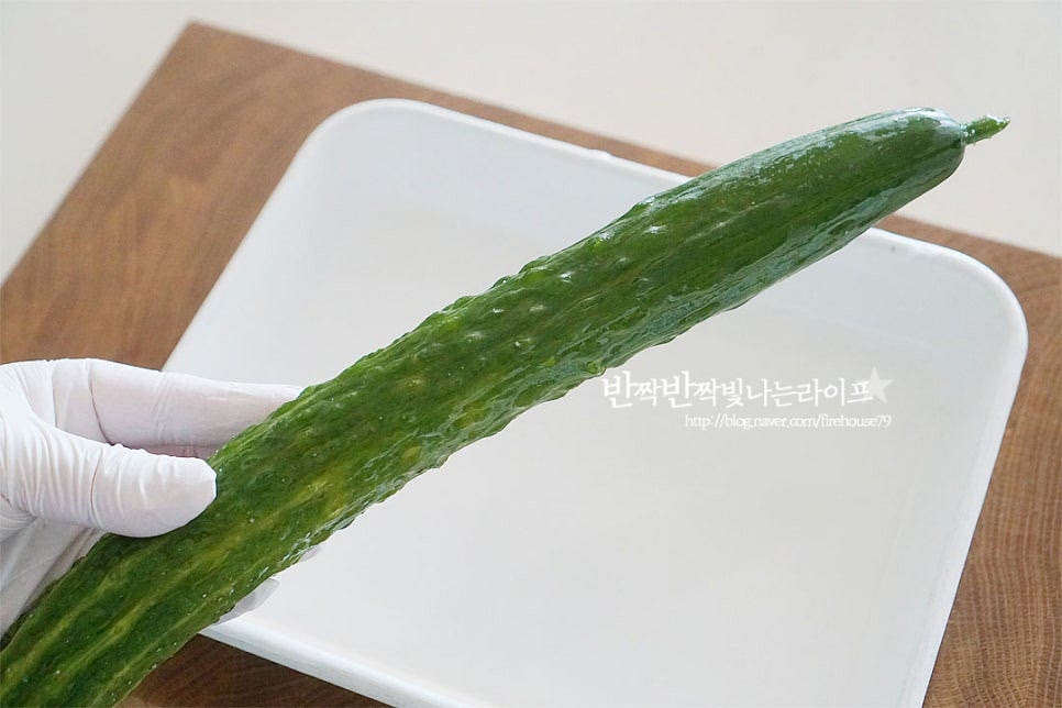 오독오독한 식감이 있는 가시오이를 준비했습니다. 굵은소금으로 살살 문질러 세척한 뒤 물기를 털어줍니다. 아삭하게 어우러지는 식감을 위해 얼기설기 껍질을 깎아줍니다. 쓴맛이 나는 양 끝 부분은 잘라내고 길게 반으로 썰어줍니다. 오이무침을 만들 때 소금에 절여서 만들기도 하지만 생오이무침을 즉석으로 만들어 먹기 위해 길게 자른 뒤 방망이로 탕탕 내리쳐줍니다. 이때 부서지지 않고 자연스럽게 으깨어질 수 있도록 힘을 조절하여 두르려주세요. 자연스럽게 갈라지면서 그 사이로 양념소스가 맛있게 스며들며 식감도 오독오독 맛있어진답니다. 한입에 먹기 좋도록 1.5cm 두께로 썰어줍니다. 만져보면 부드러운 듯 아삭하고 사이사이 갈라짐이 보이는 정도입니다.