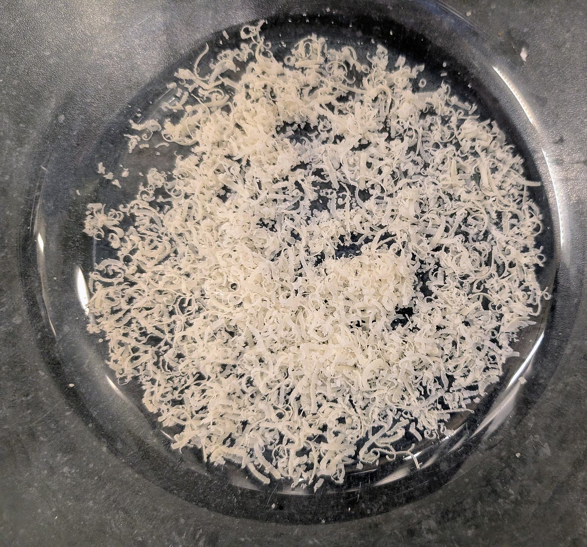 While the pasta cooks, on a glass or ceramic serving tray with tall sides, add a thin layer of grated Parmesan.