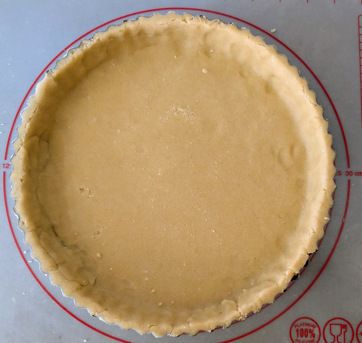Transfer the pastry disk into the lined 25cm tart tin, and press it in with your fingers, ensuring that there are no air bubbles left behind the pastry on the base or sides. Fold any excess over the edge of the tin and roll over it with the rolling pin for a nice and tidy edge top. Pop the tin in the fridge for 30 minutes to rest.