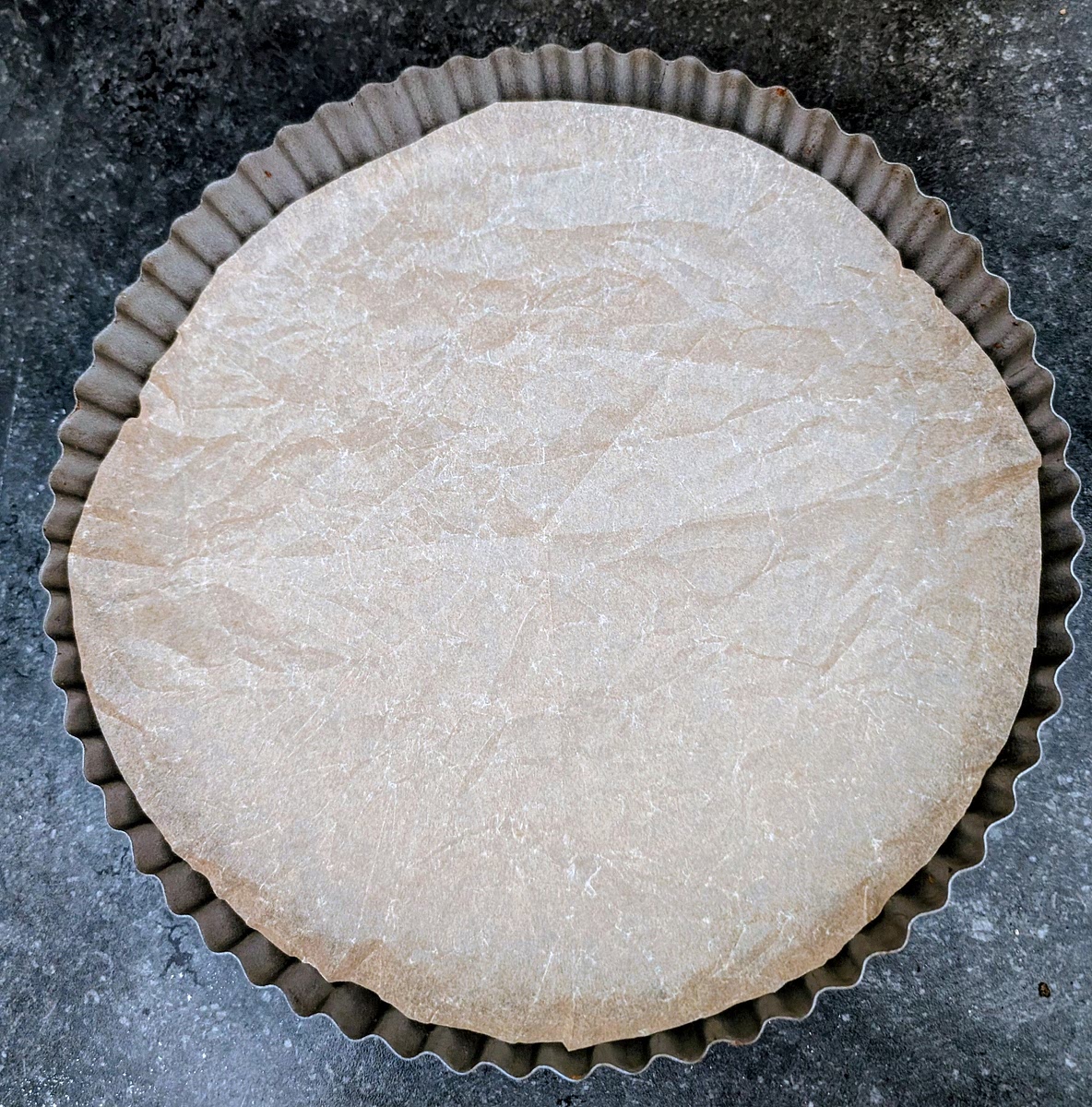 Line the bottom of a 25cm fluted tart tin with parchment paper. A tin with a detachable bottom makes unmoulding the cooked pie very easy.