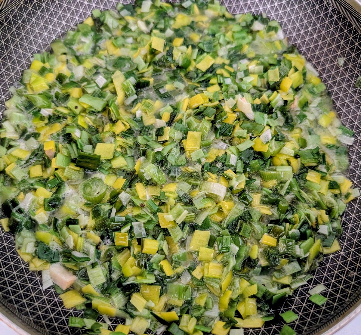 While the potatoes are cooking, warm a knob of salted butter and a swirl of olive oil in a frying pan and cook the chopped leeks and spring onions down gently until starting to soften (about 10 minutes). Adjust seasoning to taste. Add the chopped garlic and cook for a final 2 minutes.