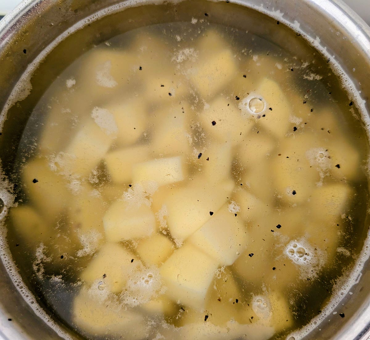 While the pastry rests and cools down, place the potato chunks in a pan of cold water. Season generously with salt (a grind of black pepper is optional) and bring it to a simmer. Cook the spuds until tender, about 10-12 minutes. Add in the wild garlic and de-stemmed spring greens to wilt for the last 30 seconds or so. Cool the leaves immediately in cold water. Drain well the potatoes and squeeze any excess water from the wilted leaves.