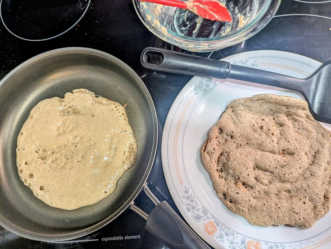 When the pan is hot, briefly remove it from the heat. Add 1/2 cup (half the mixture, 120 g) into the pan, and use a silicone spatula to spread it into a 6 inch round flatbread. Add any toppings you like, such as cheese or everything bagel seasoning