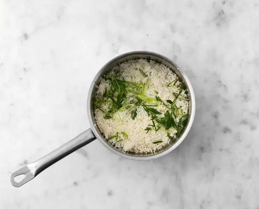 Meanwhile, thinly slice green onion.
Fluff rice with a fork, then add half the green onions and remaining lime zest.