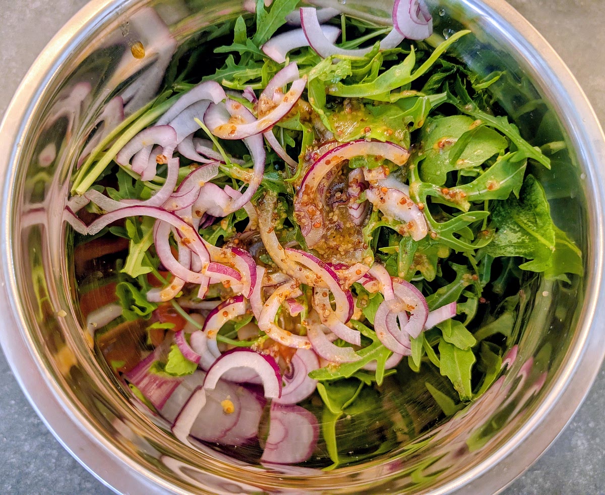 Add the beans, tomatoes, onion and rocket to a bowl. Add the dressing from the jar and toss until ingredients are well mixed and evenly coated with the dressing. Then add half of the salad to the center of the 2 plates you'll serve this on.