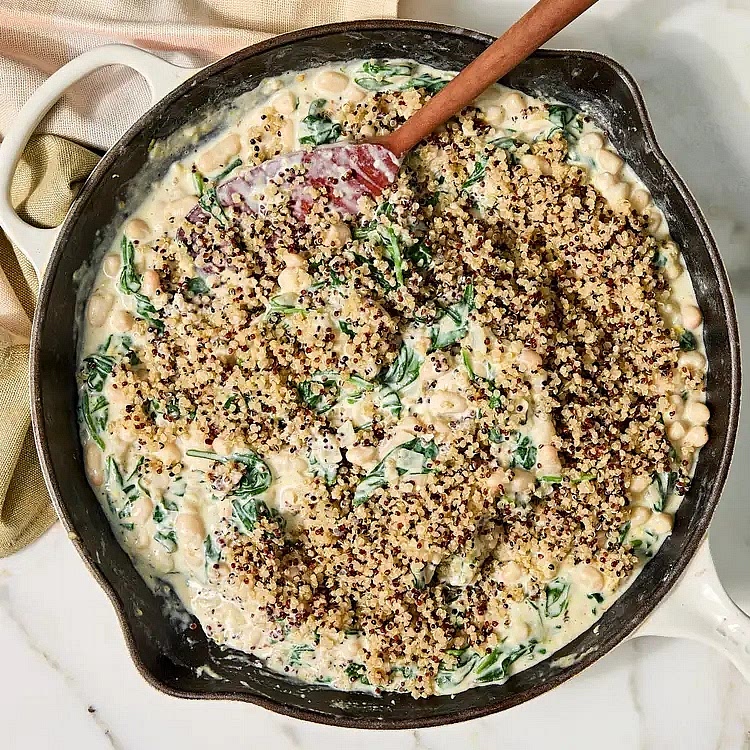 Sprinkle 2 tablespoons flour over the onion mixture; cook, stirring constantly, for 1 minute. Slowly stir in 2 cups milk; cook, stirring often, until slightly thickened, 2 to 3 minutes. Gradually add 12 ounces spinach; cook, stirring often, until wilted, 2 to 3 minutes. Stir in rinsed beans, 1 tablespoon lemon zest and ½ teaspoon salt. Add softened cream cheese; cook, stirring constantly, until melted and fully incorporated, 1 to 2 minutes. Remove from heat. Stir in the cooked quinoa until evenly combined. Sprinkle with 1 cup Parmesan.