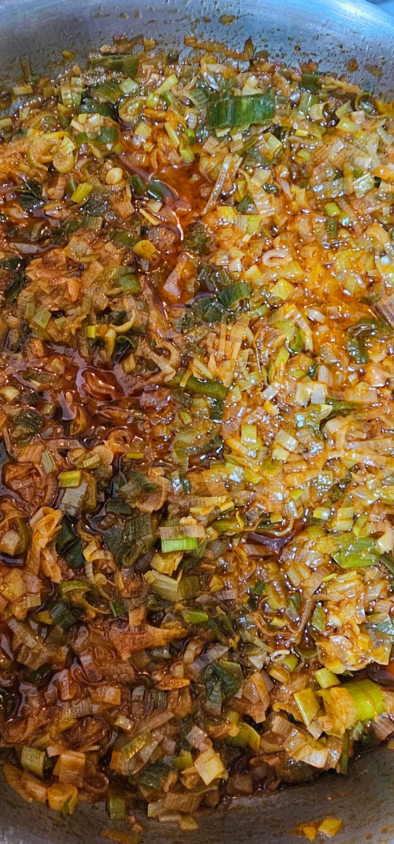 Cortar muy finita la cebolla de verdeo y saltear en una sarten a fuego bajo, que se transparente bien. Al apagar el fuego agregar pimentón ahumado, algún picante y si es necesario mas aceite o algún liquido de coccion, como para que quede un poco mas líquido. Reservar