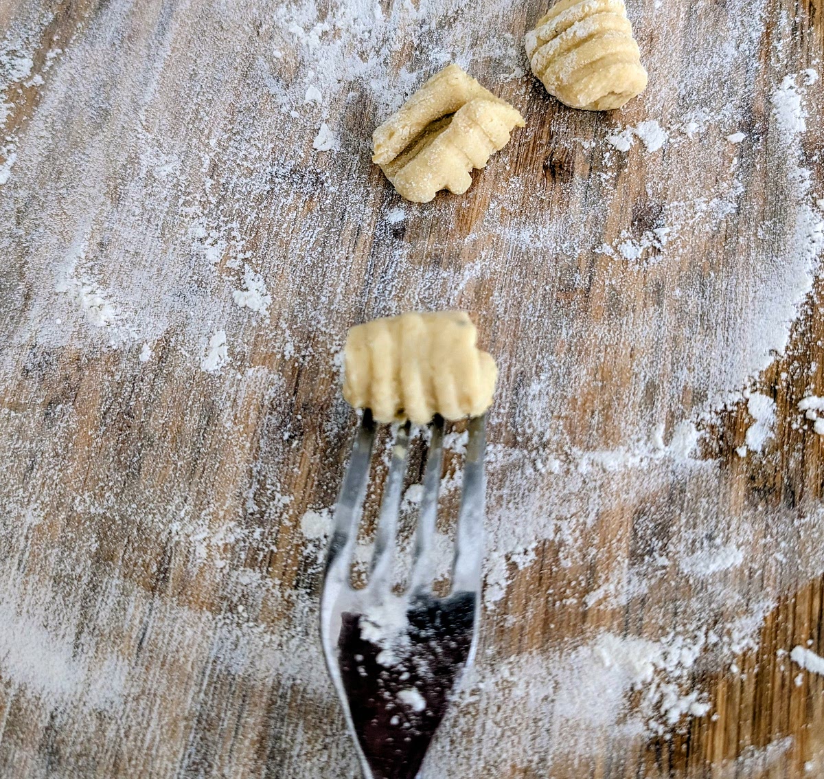 Traditionally, gnocchi are ridged to hold onto the sauce better. You can use a floured gnocchi ridger board if you have one, although the back of a fork also works well. If using a fork, you have to wipe it clean every few gnocchi so they don't stick to it. You can also skip the ridging altogether and cook the little pillows.