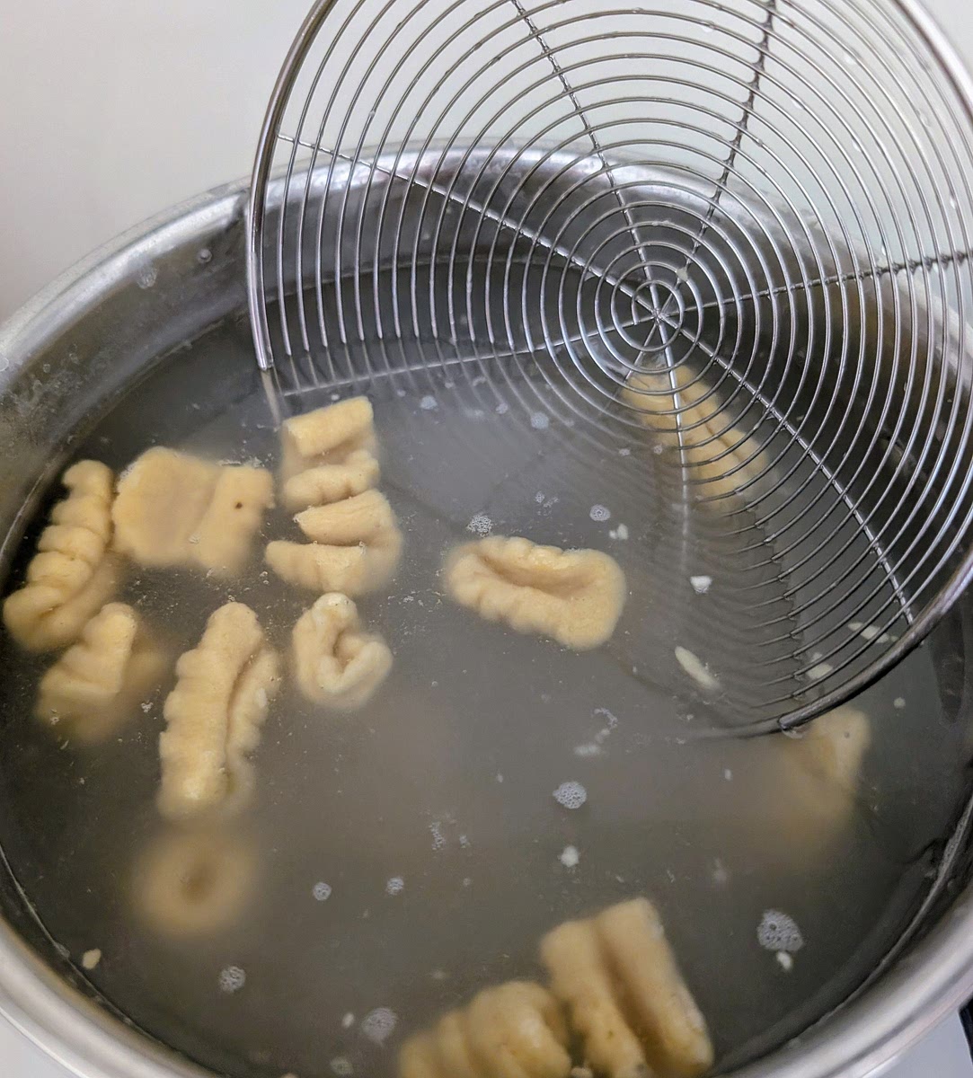 Cook the gnocchi in salted boiling water, pushing them carefully directly off the board or tray into the water. When the float to the surface (1-2 minutes) they're done. Fish them out with a slotted spoon or small sieve right as they come afloat to prevent them overcooking.