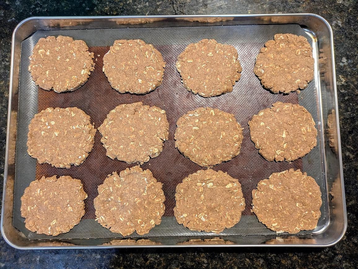 Divide the cookie dough into 12 balls, about 40 g each. Add to your parchment lined cookie sheet. Flatten down to a thin an even circle