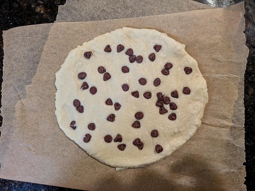Transfer your cookie dough to a small piece of parchment paper. Flatten to a 1/4" circle. Press the chocolate chips into the top