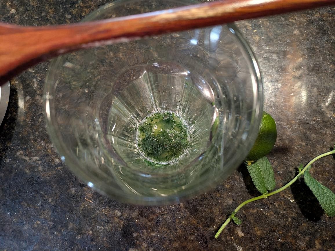 Add your mint leaves and lime juice to a tall glass. Using the back of a wooden spoon, crush together the mint and lime