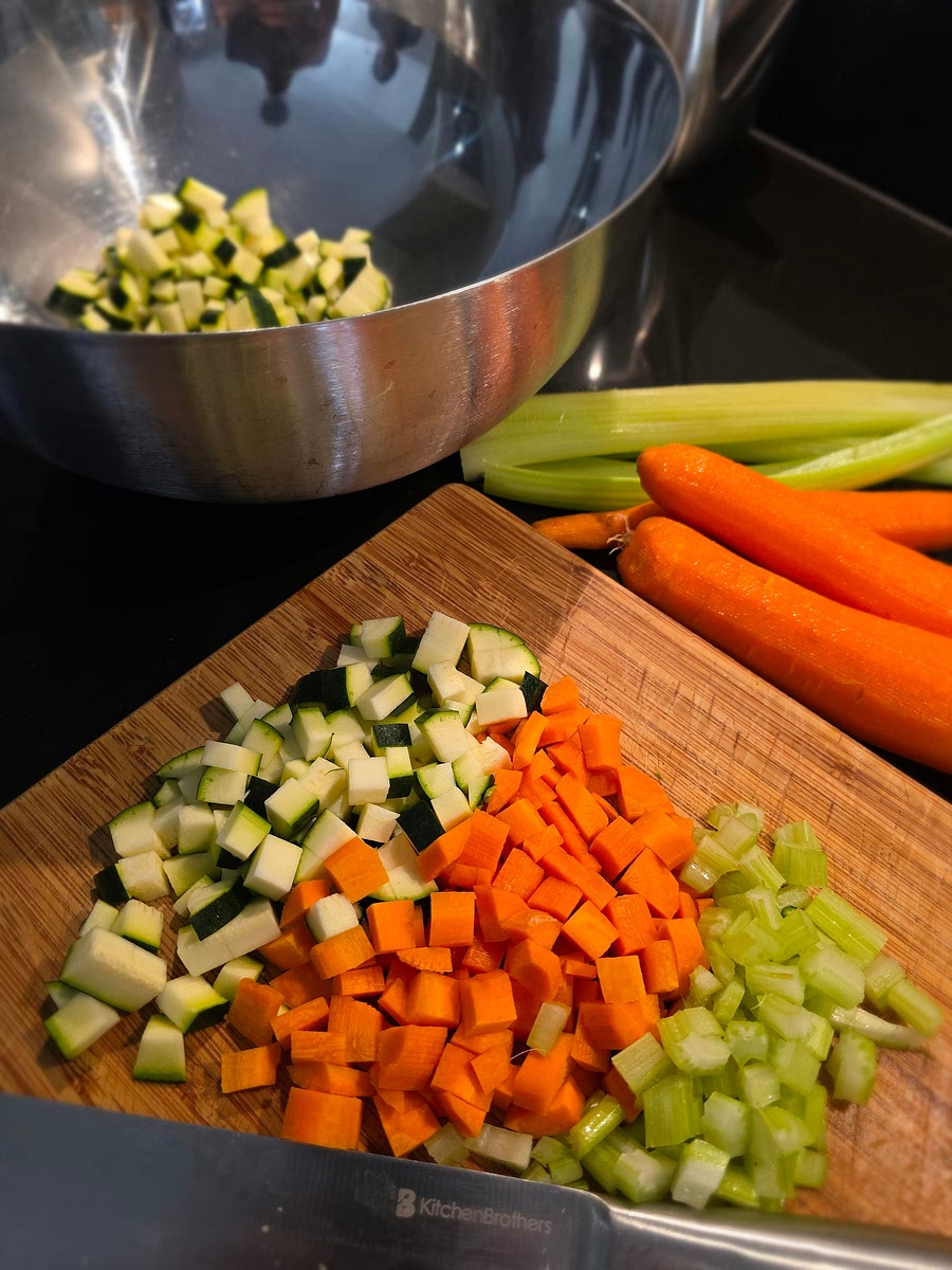 Schil de uien, penen en de bleekselderij en snijd de ui, winterpeen, bleekselderij en courgette in kleine blokjes van een halve centimeter en houdt apart