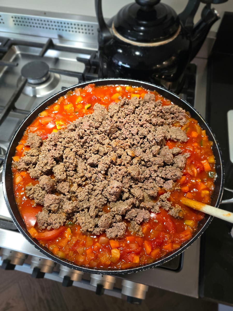 Nu kan de pan onder regelmatig roeren een aantal uur op het vuur blijven staan. Op gevoel kun je na een half uurtje het gehakt er doorgeen mixen.