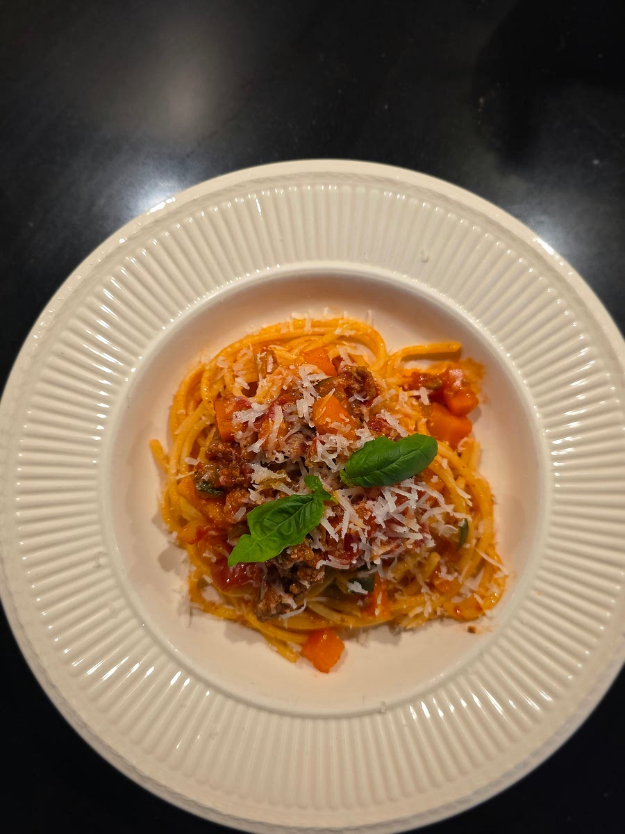 Schep de pasta met een keukentang al draaiend op een bord. Decoreer met een blaadje basilicum.