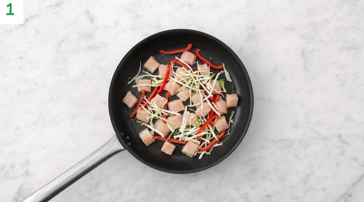 Boil a full kettle. Slice pepper into thin strips. Thinly slice the spring onion.
Heat a drizzle of oil in a large frying pan on medium-high heat.
Once hot, fry the chicken, pepper and white cabbage and broccoli slaw, 8-10 min.