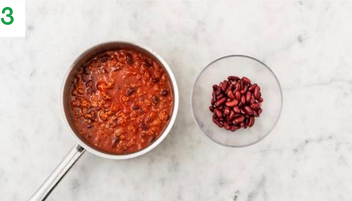 When the beef and pork is browned, drain and discard any excess fat, then season with salt and pepper.
Add the Central American style spice mix and garlic to the beef pan. Fry for 1 min.
Stir in the kidney beans (whole and mashed), tomato passata, beef stock paste, sugar and water for the sauce.