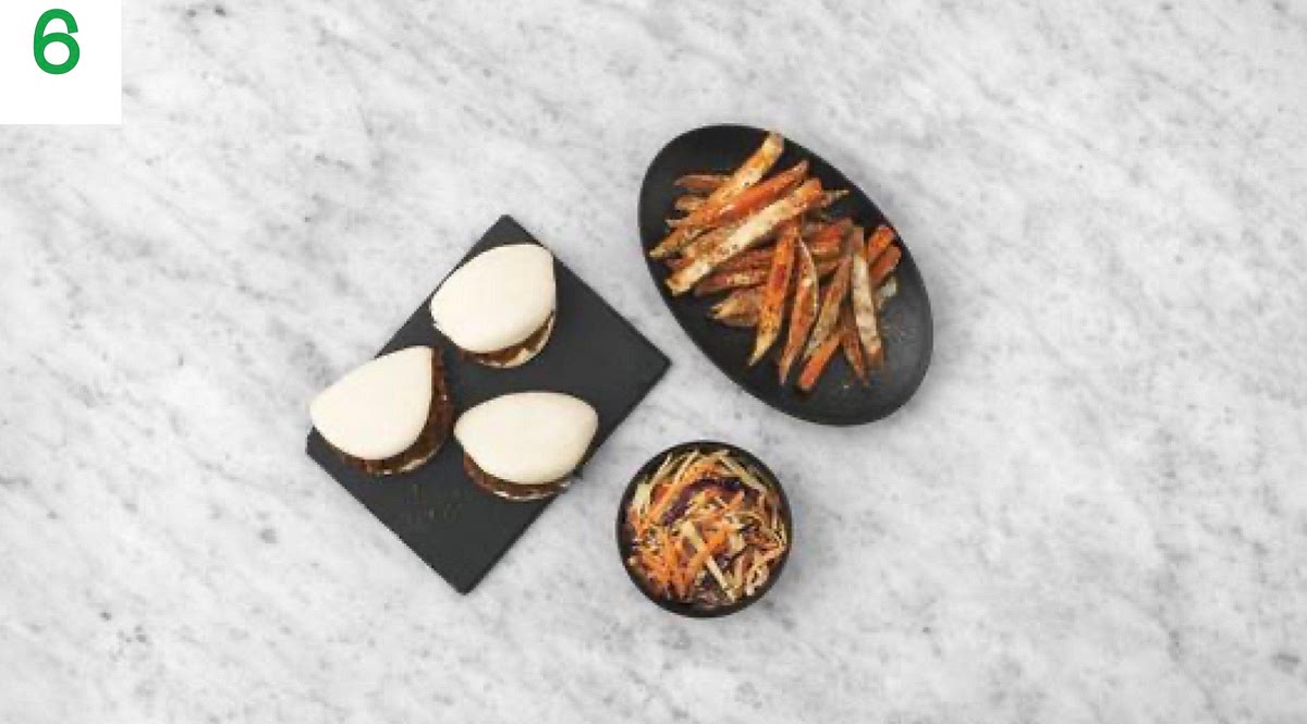 Transfer the warmed bao buns to your plates and spread the remaining mayo inside, then fill with the shredded pork. Sprinkle over the remaining chives to finish.
Serve with the cheesy sweet potato fries and slaw alongside.