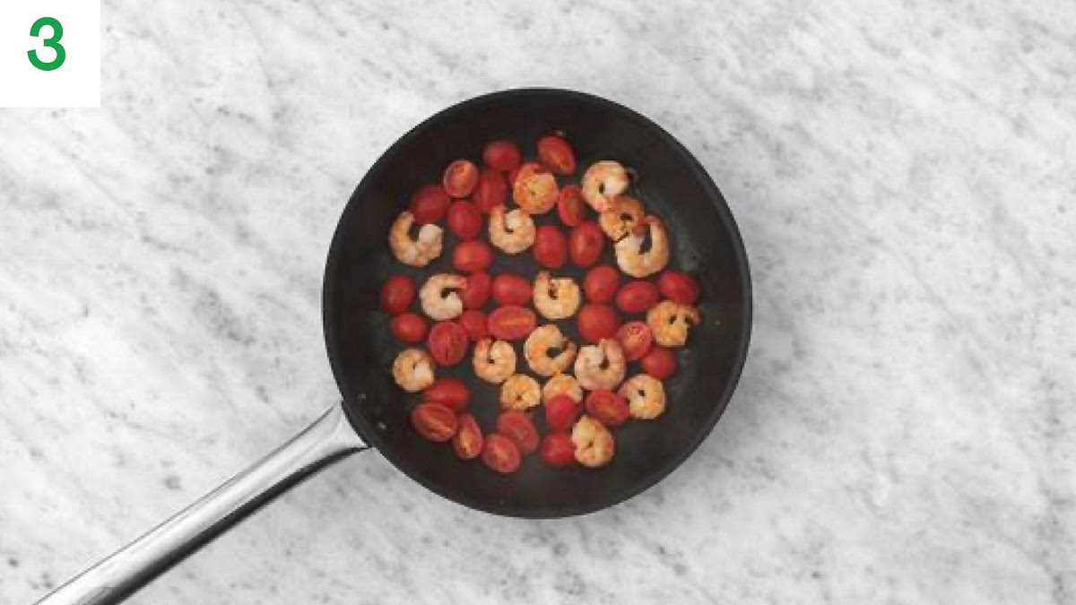 Meanwhile, drain the prawns.
Heat a drizzle of oil in a large frying pan on medium- high heat.
Once hot, add the prawns and tomatoes and stir-fry for 2-3 mins.