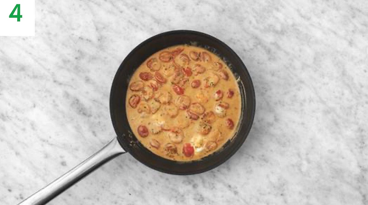 Next, stir the creme fraiche, lemon zest, tarragon, vegetable stock paste and water for the sauce into the prawns.
Bring to the boil, then turn the heat down and simmer until thickened, 3-4 mins.
Once thickened, remove from the heat.