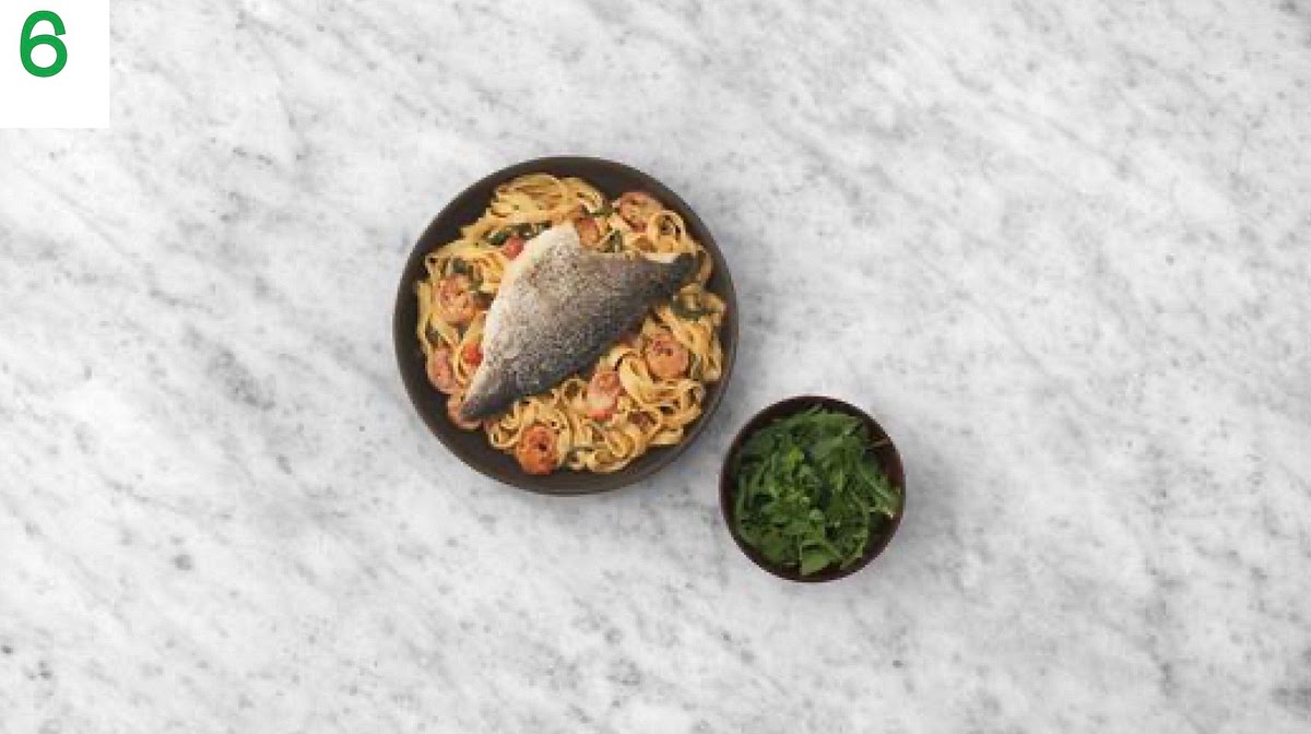 When ready, add the rocket to the dressing bowl and toss to coat.
Add a splash of water to your creamy tomato and prawn pasta if it's a little too thick, then share between your bowls.
Top with the sea bream and serve the rocket salad alongside.
