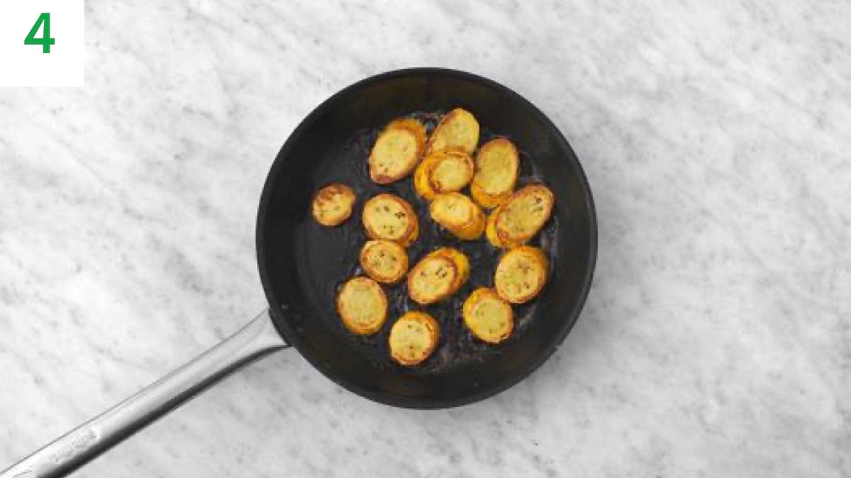 While the paste cooks, heat a drizzle of oil in a large frying pan on high heat.
When hot, add the yellow courgette and cook until charred, 3-4 mins each side. Once cooked, lower the heat and add the remaining garlic and stir-fry, 1 min more.
Remove from the heat, season with salt and pepper.
Add a pinch of lemon zest and a good squeeze of lemon juice.
Stir in the butter until melted and all combined.