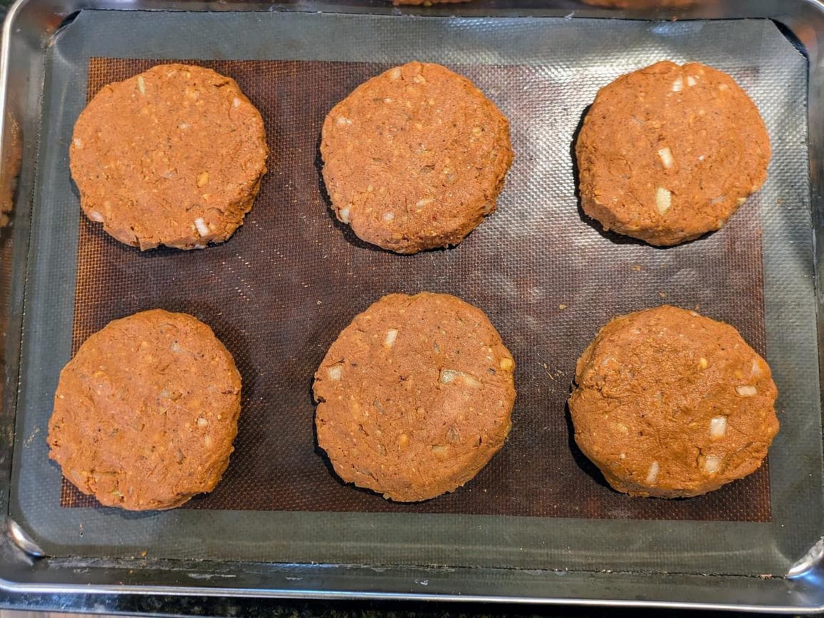 Add 6 dough balls to your pan, about 130 g each. Lightly wet your hands, and shape into patties. Wearing kitchen gloves helps to prevent sticking