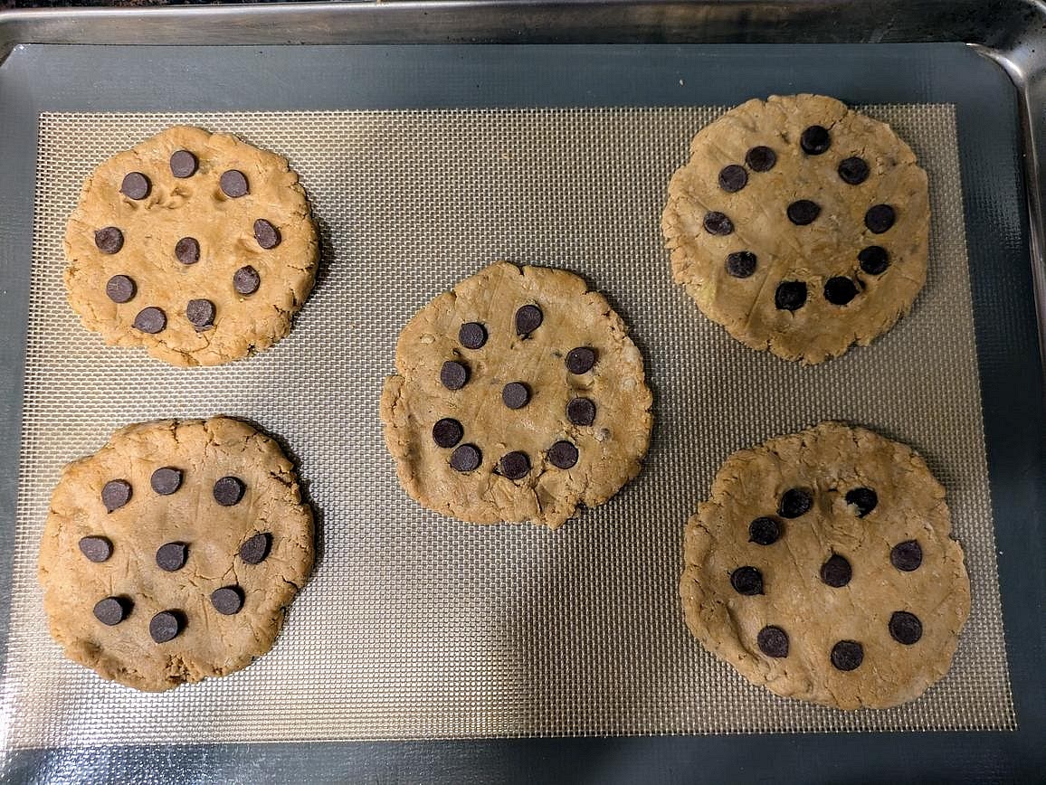 Scoop the dough into large balls onto the pan, about 68 g each. Flatten into 1/4" thick cookies. Top with chocolate chips