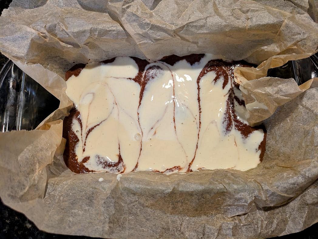 Transfer the cheesecake batter to the pan on top of the brownie layer. Optionally swirl together the brownie and cheesecake layers with a butter knife.