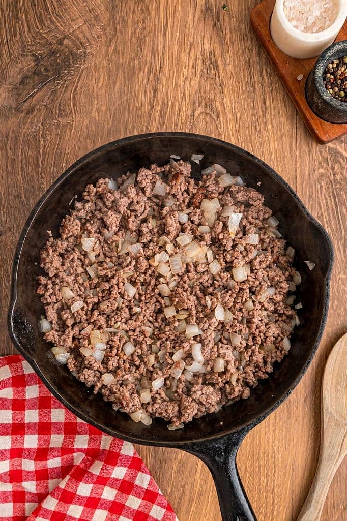 In a large skillet over medium heat, cook 1 pound ground beef with 1 medium onion, diced, breaking up the meat as it cooks. Once the beef is browned and fully cooked, drain any excess grease if needed.