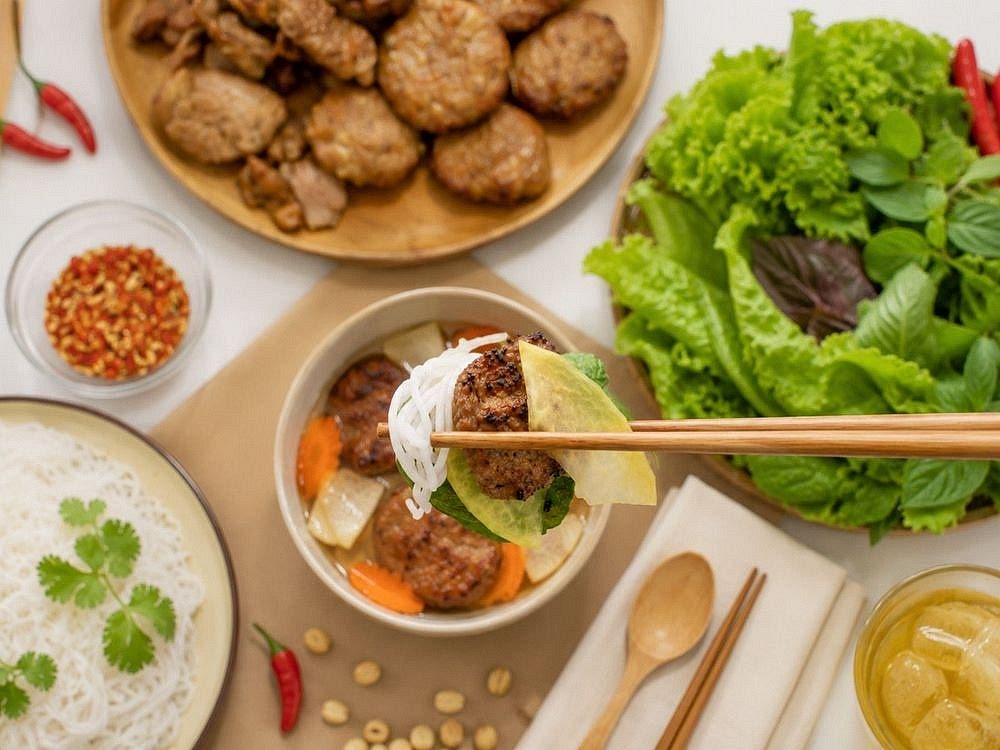 Assemble And Serve
Divide the warm dipping sauce among individual serving bowls. Add several grilled pork patties, pork belly slices, and pickled vegetables to each bowl. Serve the rice vermicelli, remaining grilled pork, fresh herbs, bean sprouts, lime wedges, and extra chili separately. To eat, place a small portion of noodles and herbs into the warm dipping sauce, then enjoy them with the grilled pork and pickled vegetables.