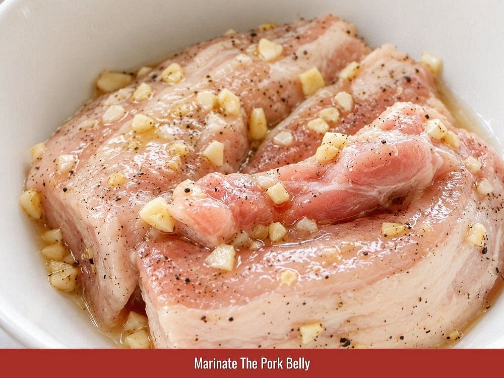 Marinate The Pork Belly
Combine the pork belly with the minced garlic, salt, bouillon powder, fish sauce, sugar, and ground pepper. Rub the seasonings evenly into the meat and let it marinate for 20 minutes.