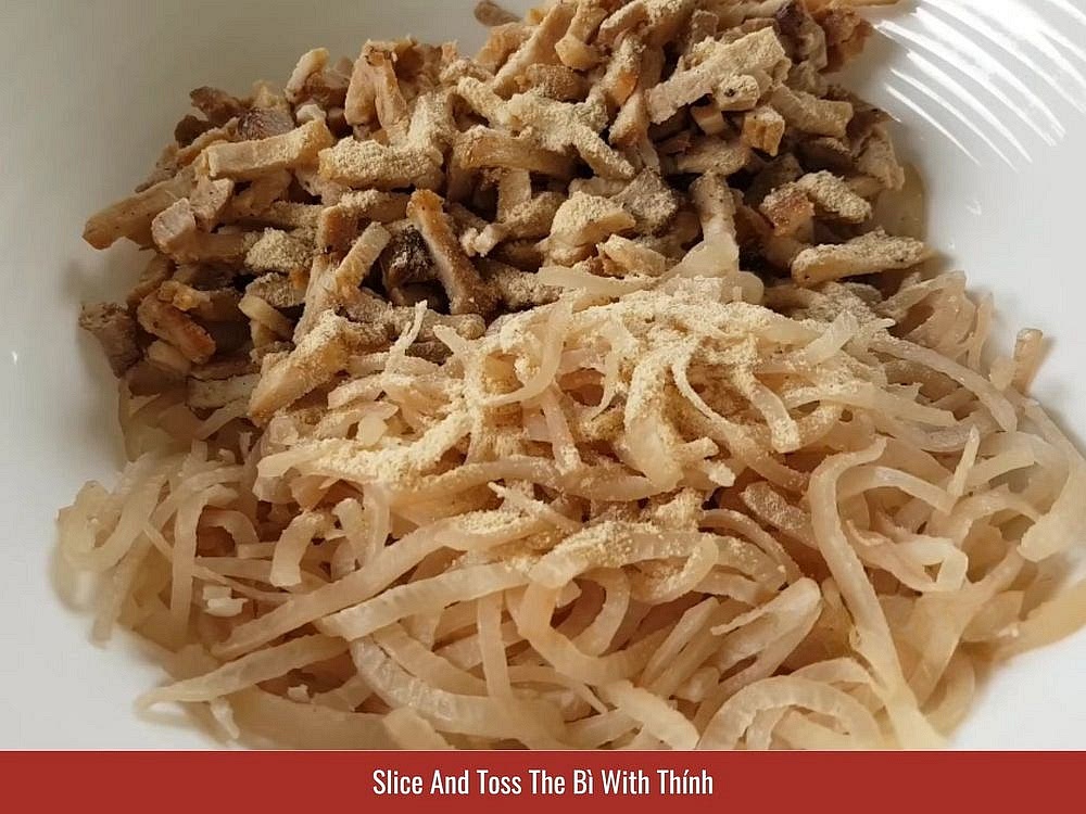 Slice And Toss The Bì With Thính
Slice the cooled pork skin into thin strips about 5cm long. Cut the cooled braised belly as thin as you can manage, then into small strips, and tip both into a large bowl. Add 1 tbsp garlic powder and 2 to 3 tbsp of the toasted rice powder. Toss until everything wears a dry, even coat. That thính is what gives bì its nutty smell and that soft, powdery-crunchy bite, and making it from scratch beats the store-bought kind.