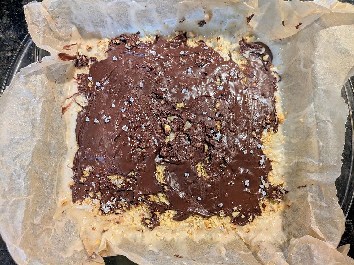 Pour the melted chocolate over the peanuts, and spread to an even layer. Optionally top the melted chocolate with flaky salt.