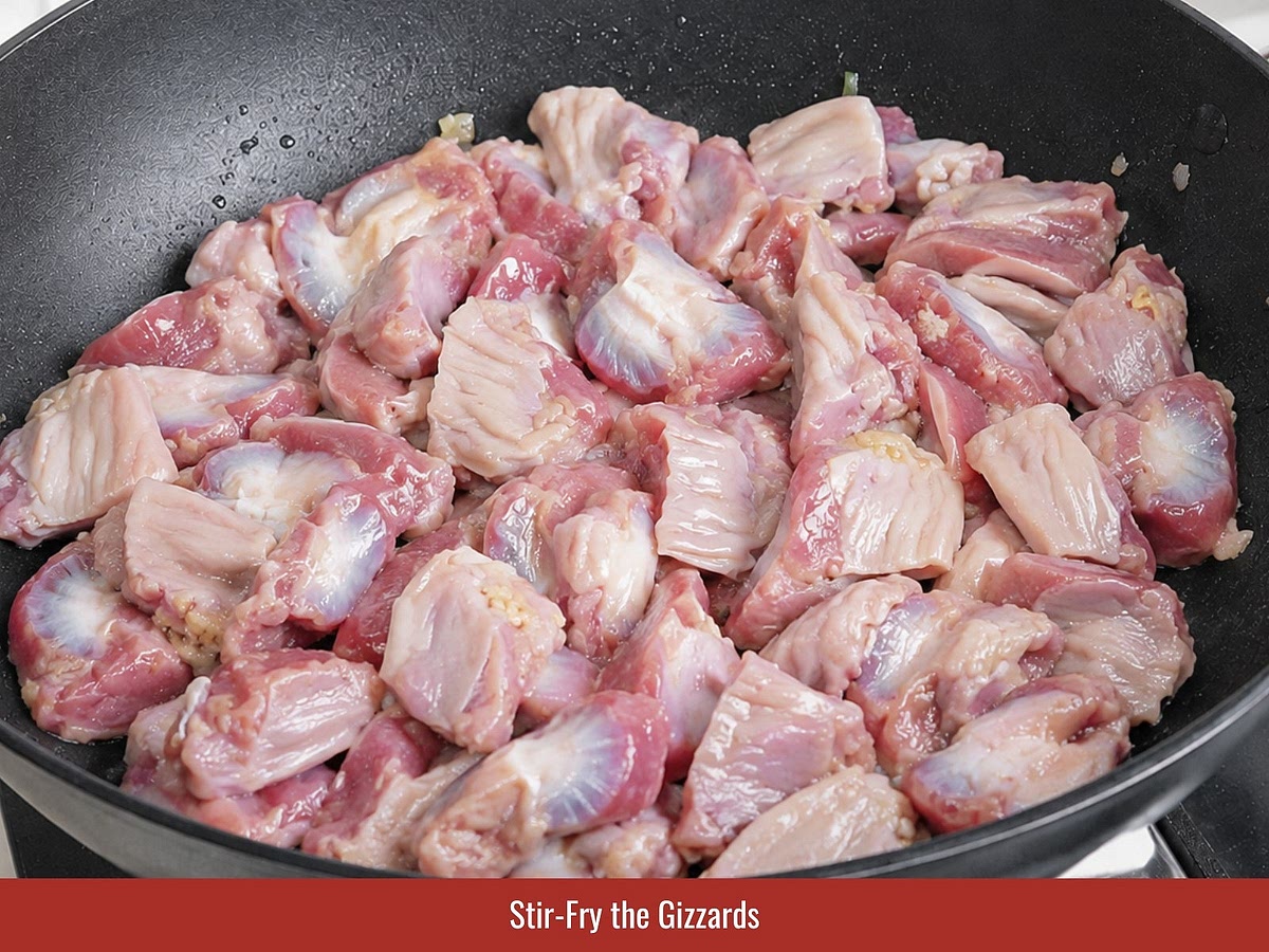 Clean and slice chicken gizzards, then stir-fry them with rendered chicken fat, shallots, garlic, seasoning, and broth until tender.