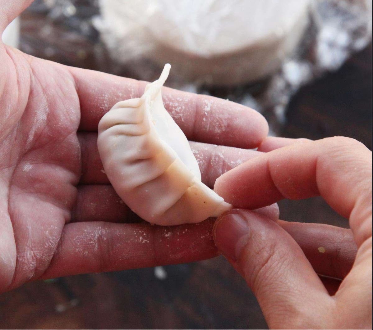 Mix the meat with all the ingredients. After the dough has cooled, take it out and cut it into about 20 pieces. Roll out the individual pieces of dough into patties and start filling them with the meat mixture. Make sure the dumplings are tightly packed.