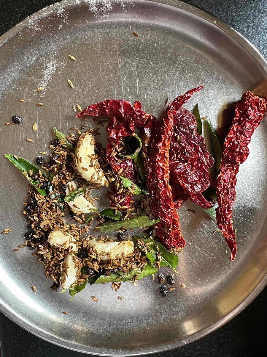 Add dried red chillies to the mix and fry for a few seconds after switching off the flame. Once the chillies have fried, remove all the ingredients from the tadka pan and keep aside to cool.
