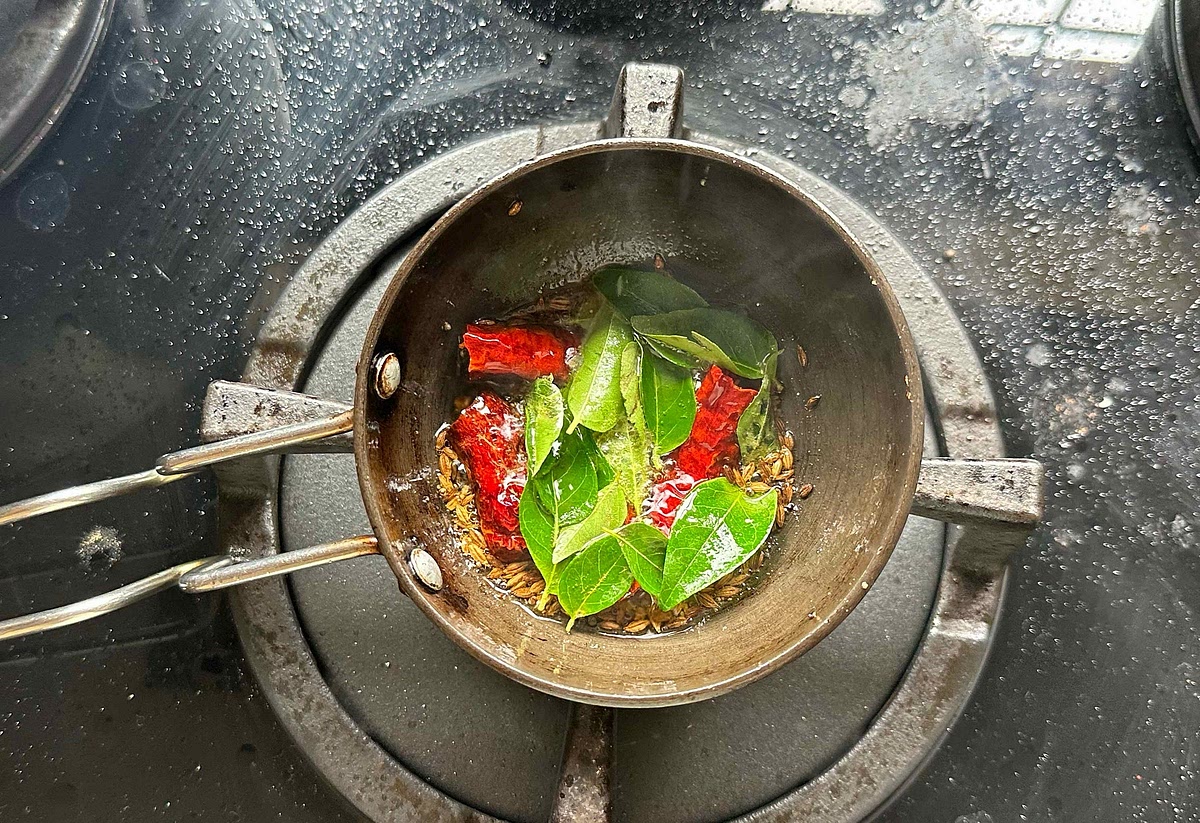 After the mustard seeds splatter, add curry leaves and dried red chillies.