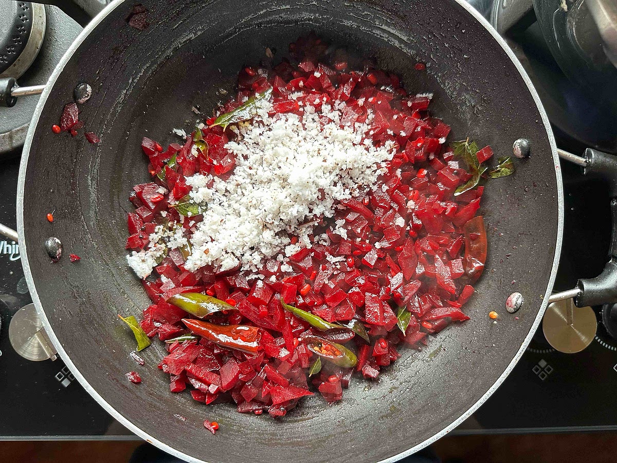 Once the beetroot has cooked and water has fully evaporated, add grated coconut to the kadhai, and mix well.