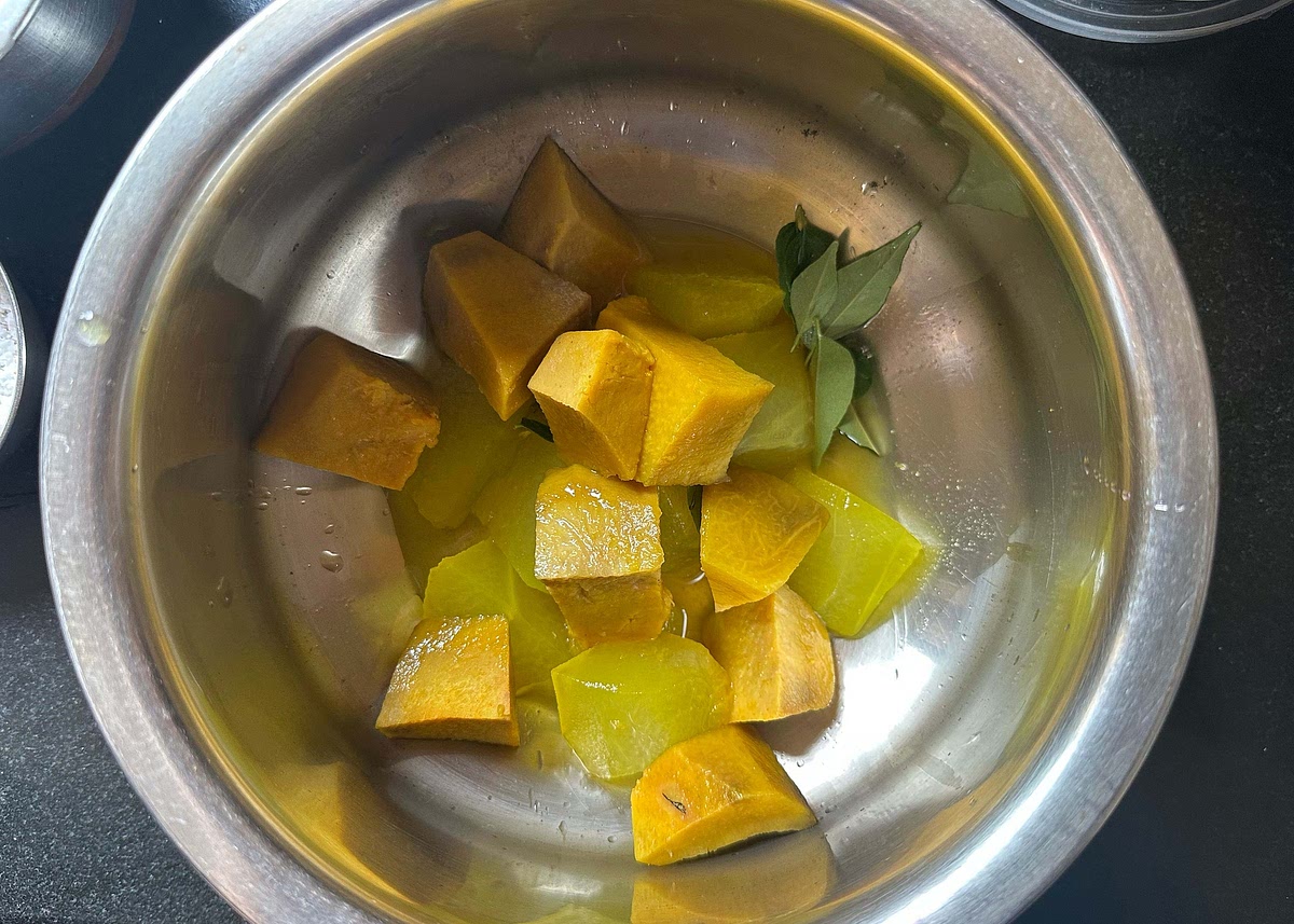 In a kadhai, add the cooked yam and white pumpkin chunks with a few curry leaves.