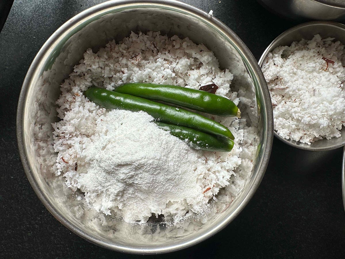 In a blender, take grated coconut, rice flour, and green chillies. Add a little water.