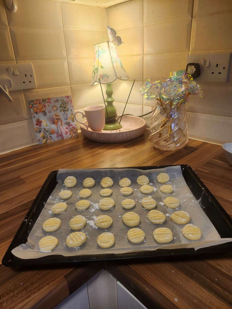 On a lined baking tray, add a small ball of dough, about the size of a cherry. Dip a fork in cornstarch, and press down on the cookies to flatten and shape. If you are making coconut or almond variations, spinkle on your toppings here. Once you have done this, put the tray in the freezer for 5-10 minutes. This helps the cookies hold shape when cooking.