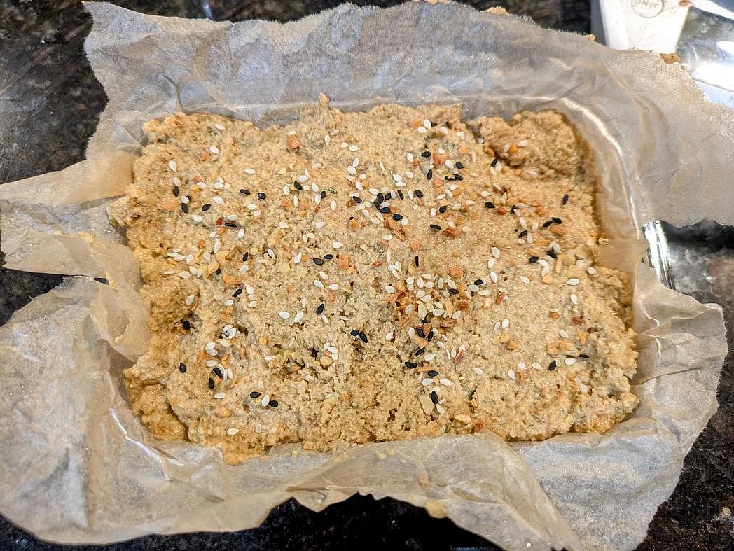 Transfer the batter to a large bowl. Add in psyllium husk and baking powder. Mix together with a silicone spatula, and transfer to your prepared pan. Optionally top with everything bagel seasoning.