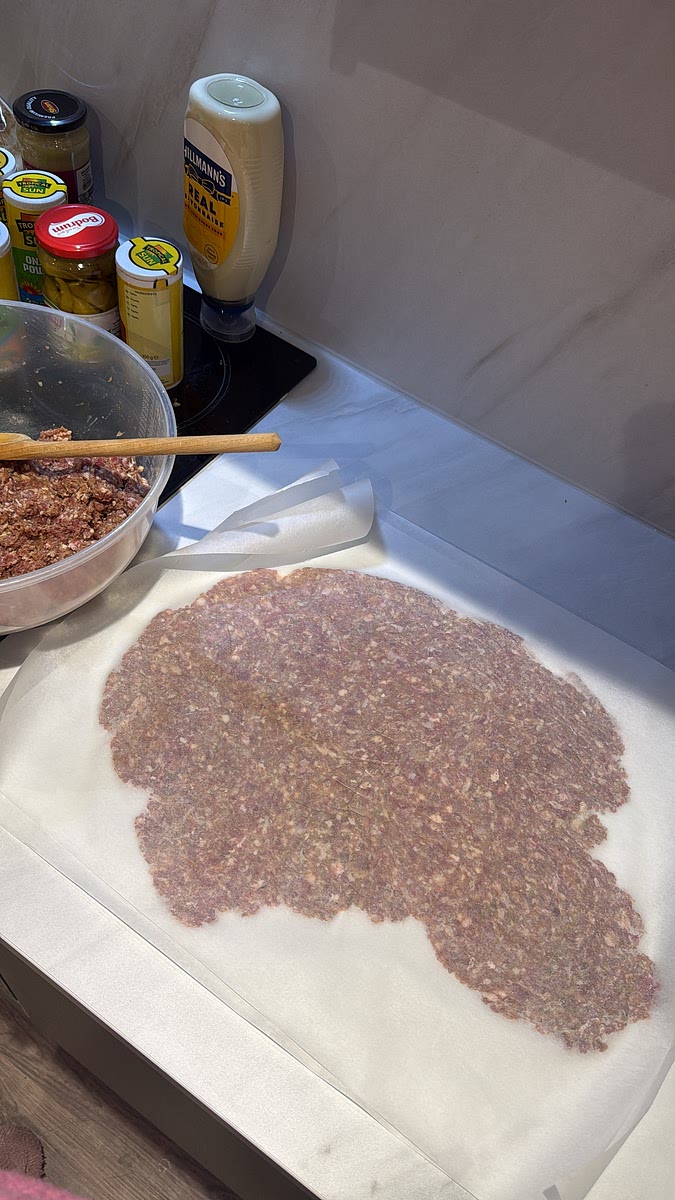 Take two sheets of baking paper and place some of the meat mixture between them. Press or roll the mixture out as thinly as possible. Remove the top sheet of baking paper carefully — keep it because you can reuse it for the next batch!
