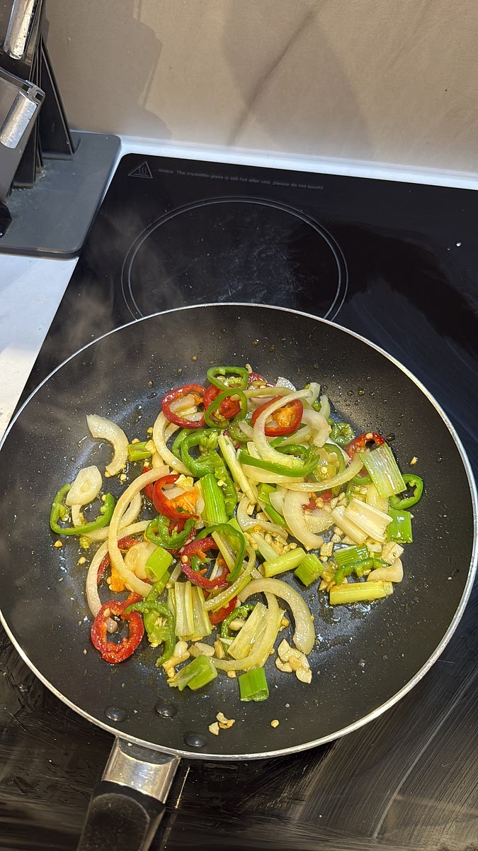 Remove most of the frying oil, leaving around 1–2 tablespoons in the pan. Add the onion, garlic, spring onion and chillies and stir-fry over medium-high heat until fragrant and slightly softened while still retaining some bite.