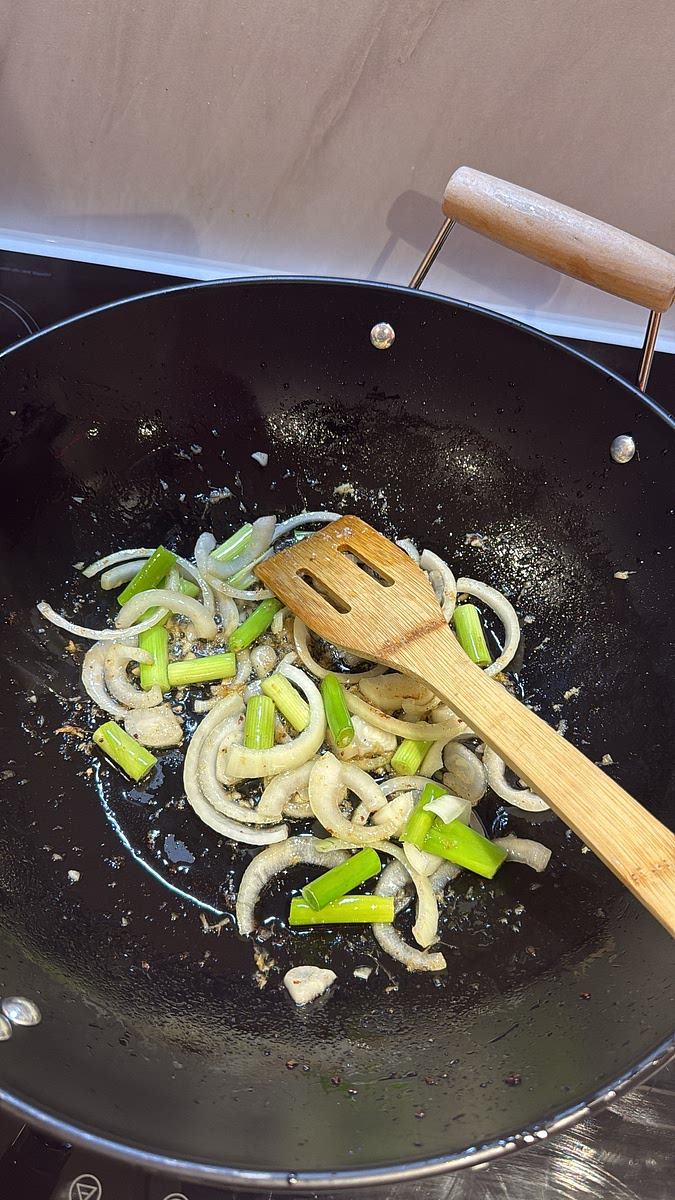 Carefully remove most of the frying oil, leaving some in the wok/pan. Add the garlic, ginger, sliced white onion and the chunky pieces of spring onion. Stir-fry for 1–2 minutes until fragrant and the onions have started to soften while still retaining some bite.
