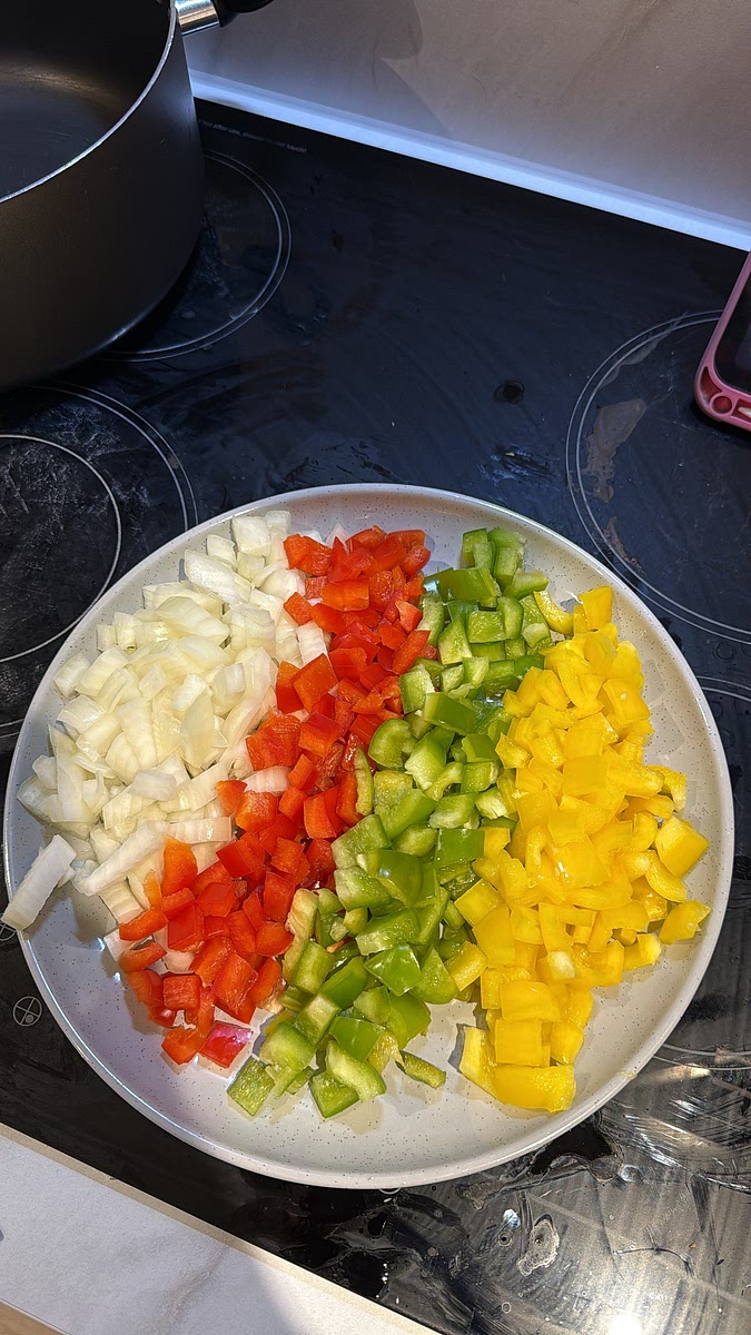 Dice the onion, then deseed and chop the red, yellow and green peppers into bite-sized pieces. Set everything aside ready for cooking. you can chop some scotch bonnet as well if you want it hot