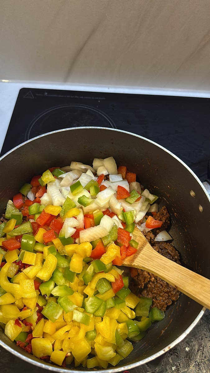 Add your diced onions and red, yellow and green peppers. Stir everything together and allow the vegetables to begin softening.