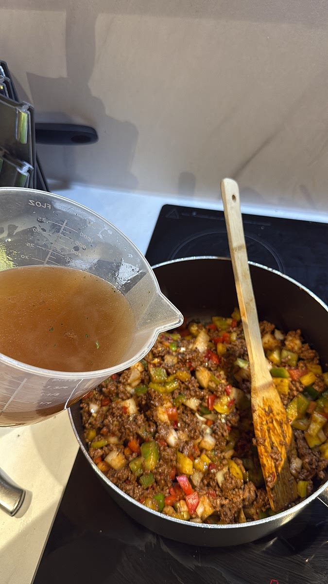 Pour in approximately 400–500ml beef stock, stirring well to combine it with the seasoned mince and tomato base.