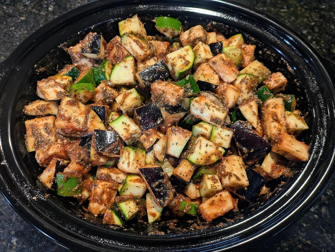 Cut your zucchini and eggplant into large chunks, and add to a large slow cooker with crushed tomatoes, basil, oregano, salt, pepper, and water.